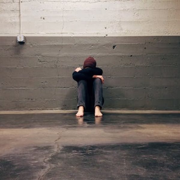 Síndrome. Fotografía de una persona sentada con la cabeza entre las piernas