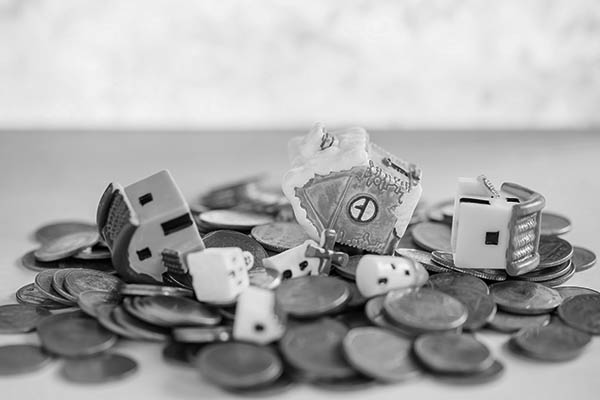 Mini house on pile of coins with green blur background.