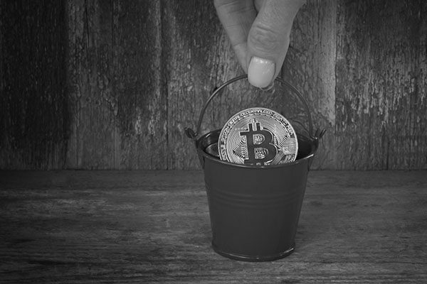 Pot with golden coin bitcoin in female hand. old wooden backgrou